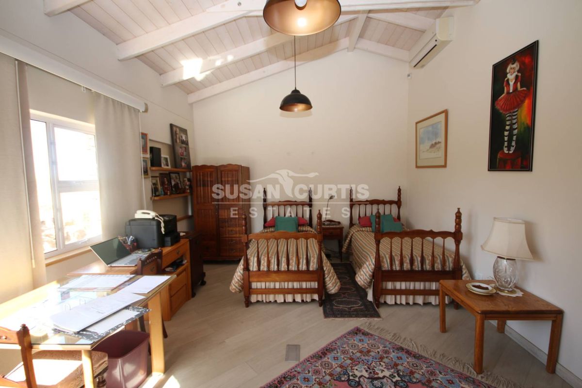 Spacious bedroom featuring an exposed timber vaulted ceiling, split-system air conditioning, and large windows providing natural light.
