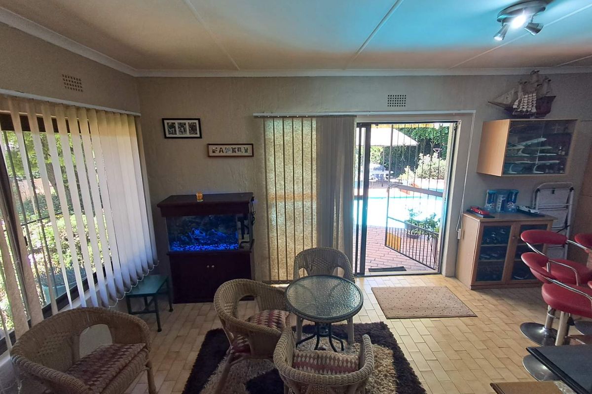Living area featuring tiled flooring, vertical blinds, and a sliding glass door providing direct access to the outdoor pool area.