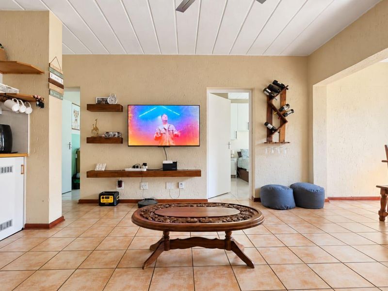 Open-plan living and kitchen area featuring tiled floors, textured walls, and a timber-look ceiling, creating a functional and connected living space.