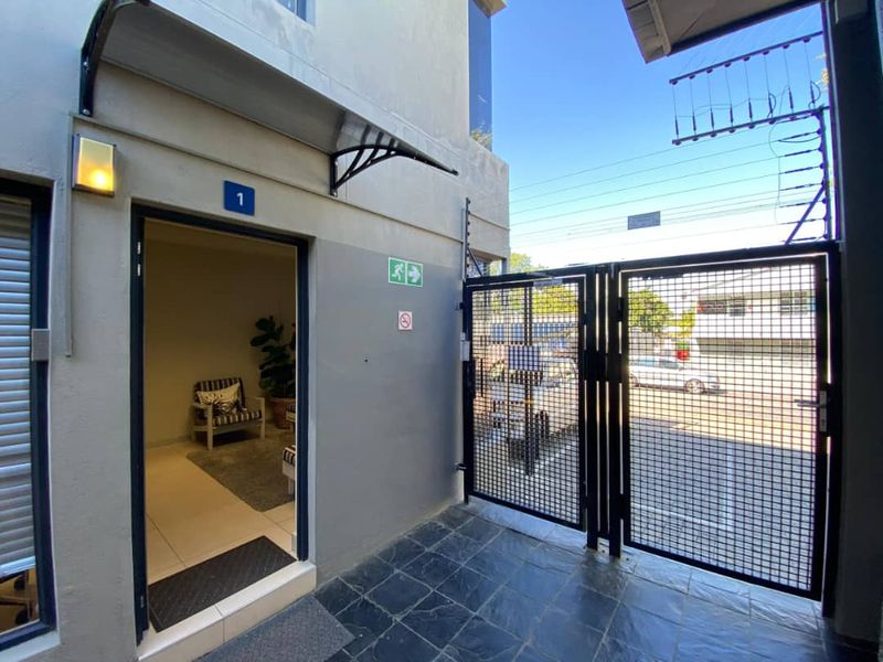 Entrance area to office unit featuring a secure metal gate, electric fencing, and a covered entryway with tiled flooring.