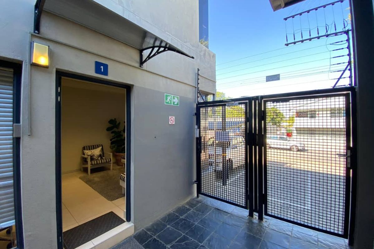 Entrance area to office unit featuring a secure metal gate, electric fencing, and a covered entryway with tiled flooring.