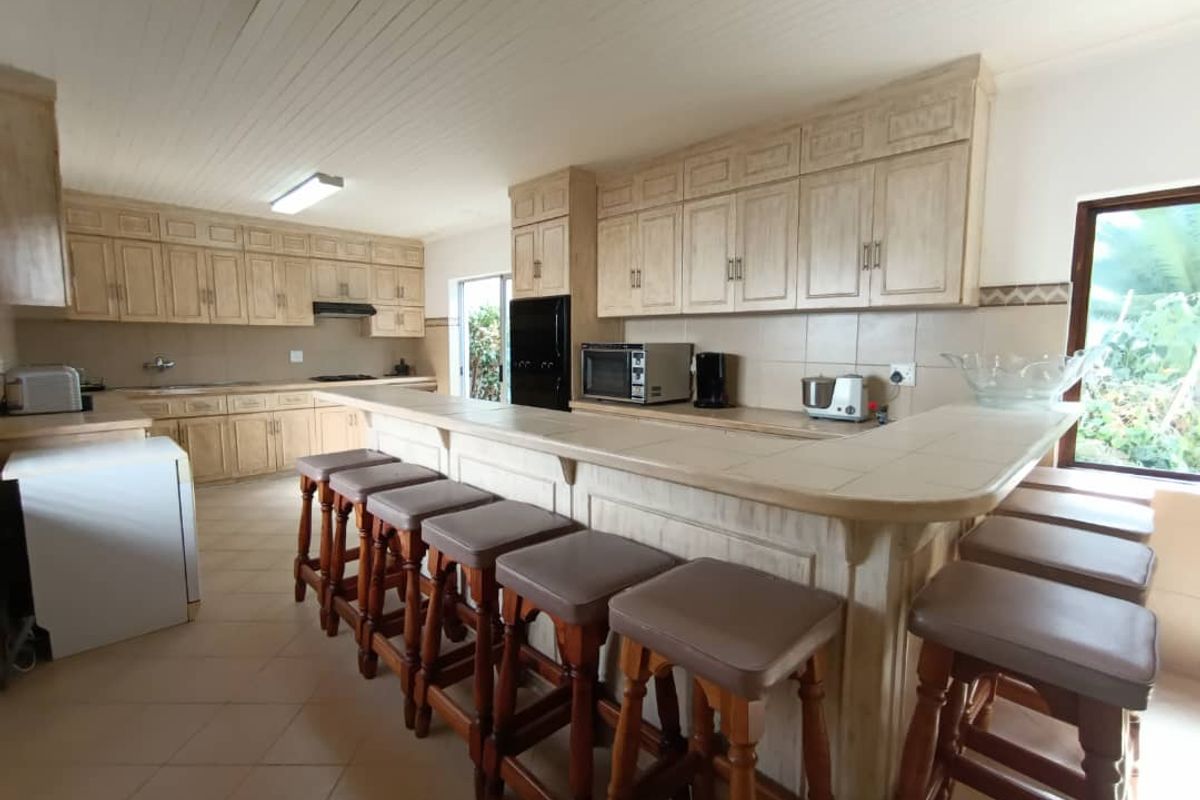 Spacious kitchen featuring extensive built-in cabinetry, tiled countertops, and a large breakfast bar, offering ample storage and workspace for casual dining.