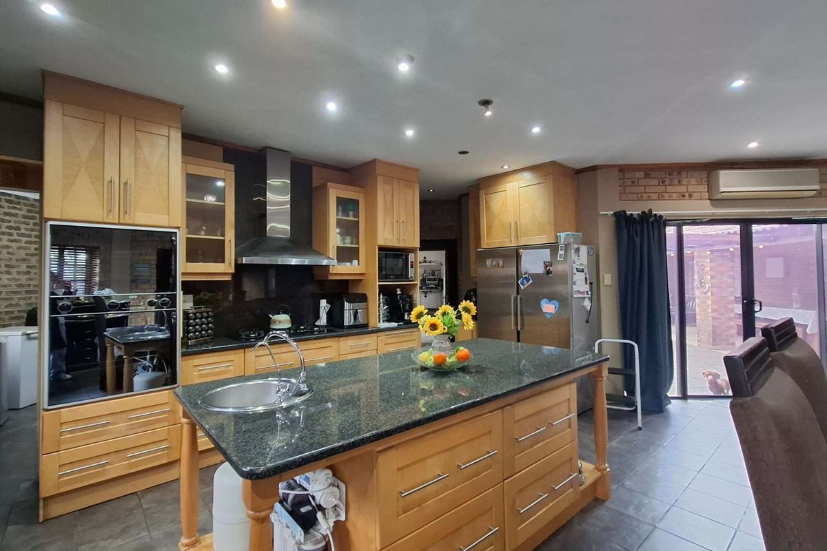 Spacious kitchen featuring a central island with granite countertops, built-in oven, extractor fan, and direct access to the outdoor patio area.