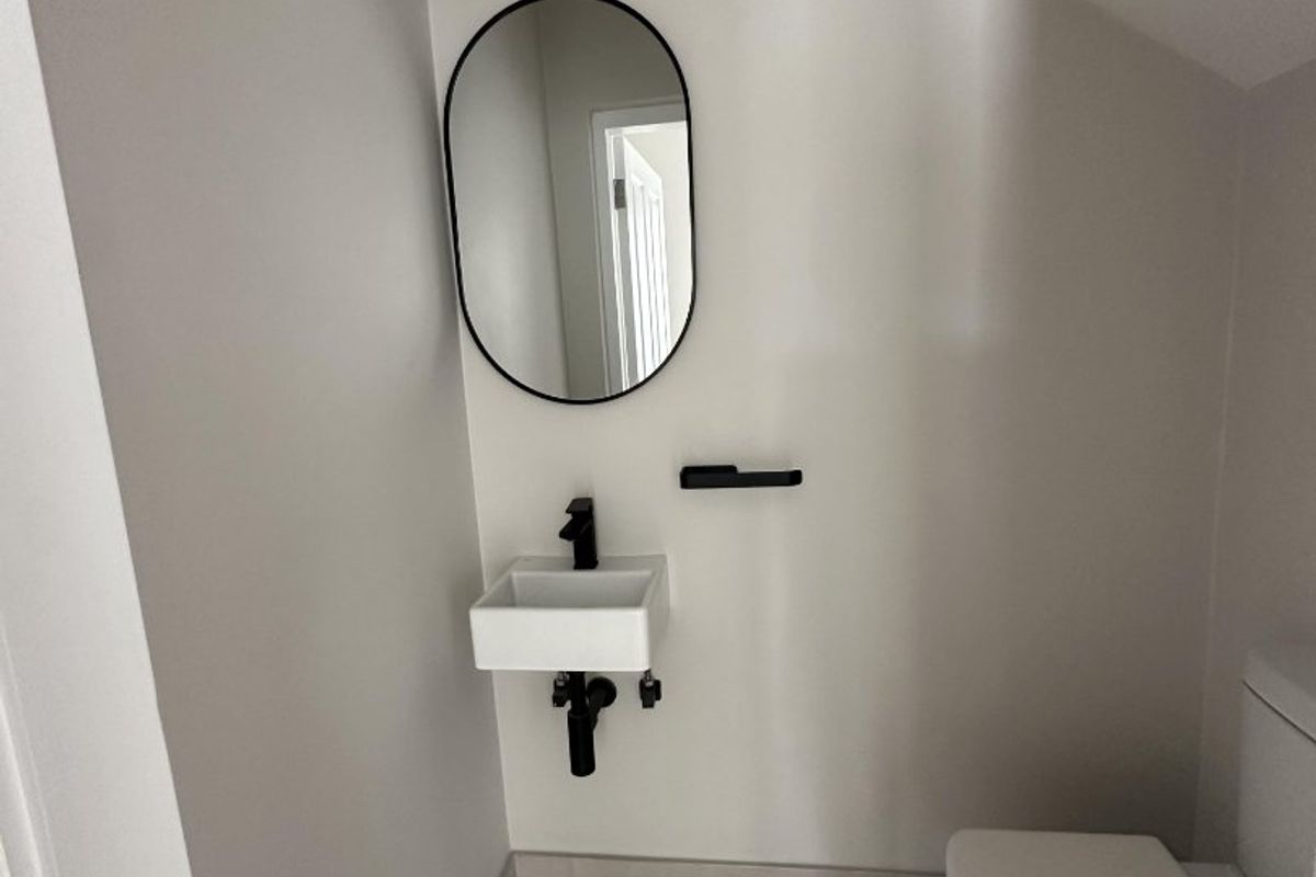 A modern, compact powder room featuring a wall-mounted basin, black fixtures, and a clean, minimalist aesthetic.