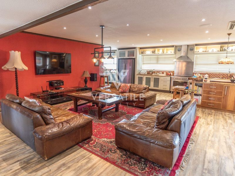 Spacious open-plan living area featuring a kitchen with built-in appliances and a comfortable lounge space with recessed lighting and wood-look flooring.