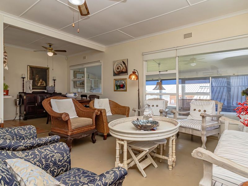 A spacious living room featuring a ceiling fan, neutral walls, and large sliding glass doors that provide access to an outdoor area.