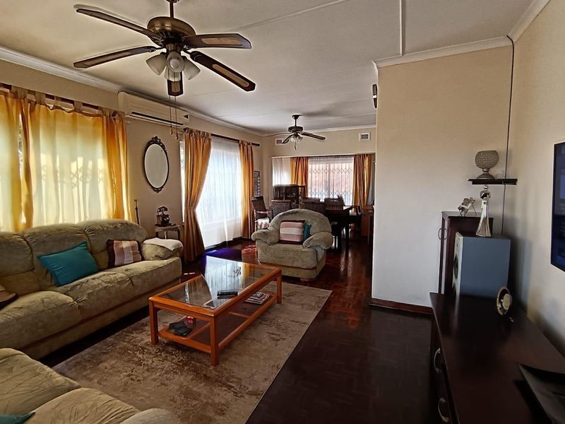 Spacious open-plan living and dining area featuring classic parquet flooring, ceiling fans, and split-system air conditioning.