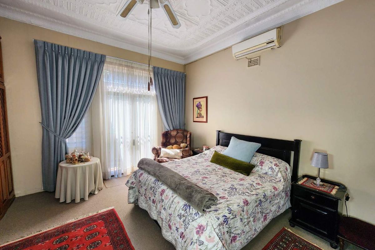 A spacious bedroom featuring a decorative plaster ceiling, ceiling fan, split system air conditioning, and direct access to an outdoor area via sliding glass doors.