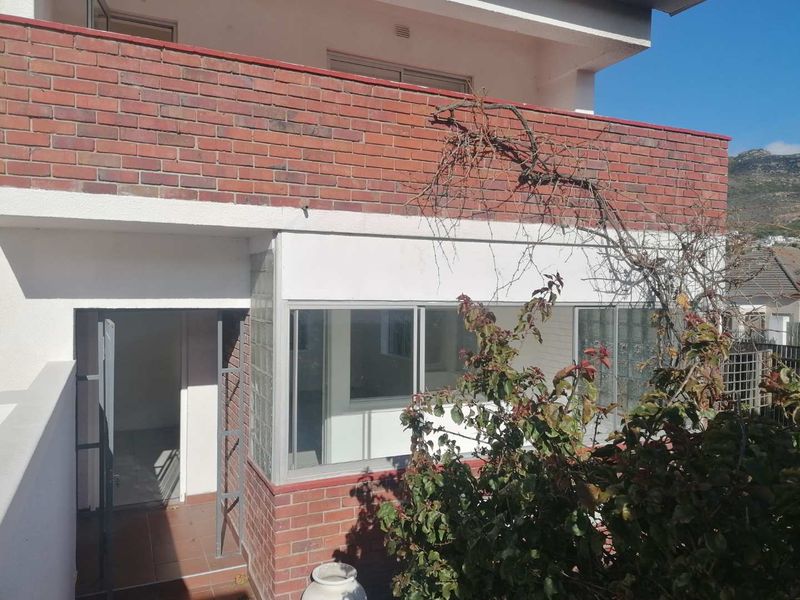 Rear exterior view of the apartment featuring a brick balcony, glass block accents, and a tiled patio entrance.