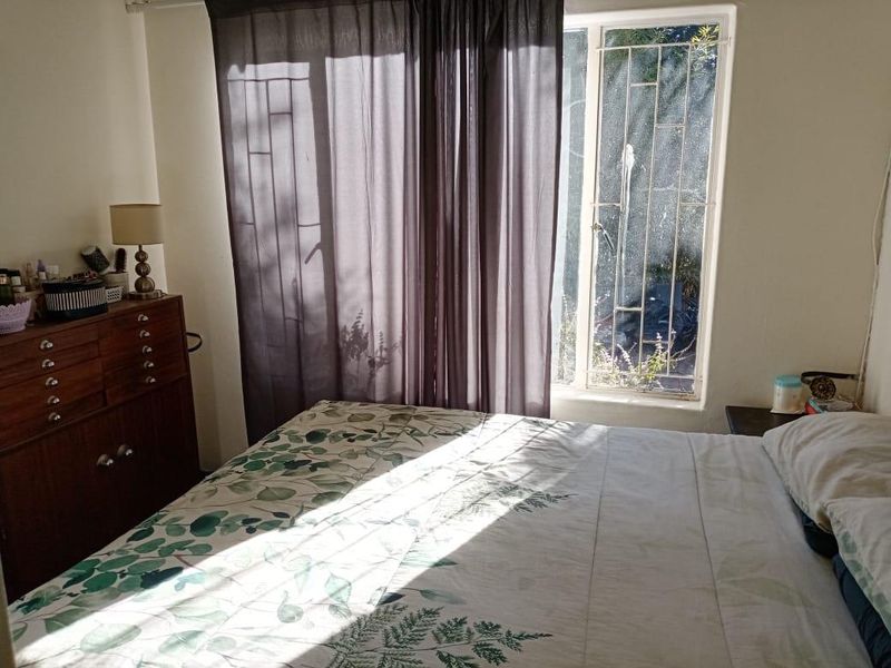 A bedroom featuring a window with an integrated security gate and curtain tracks, allowing natural light into the space.