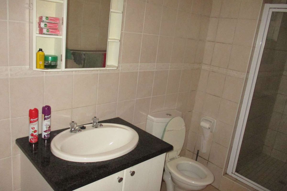 A functional bathroom featuring a vanity with granite countertop, integrated basin, toilet, and a separate shower enclosure with tiled walls.