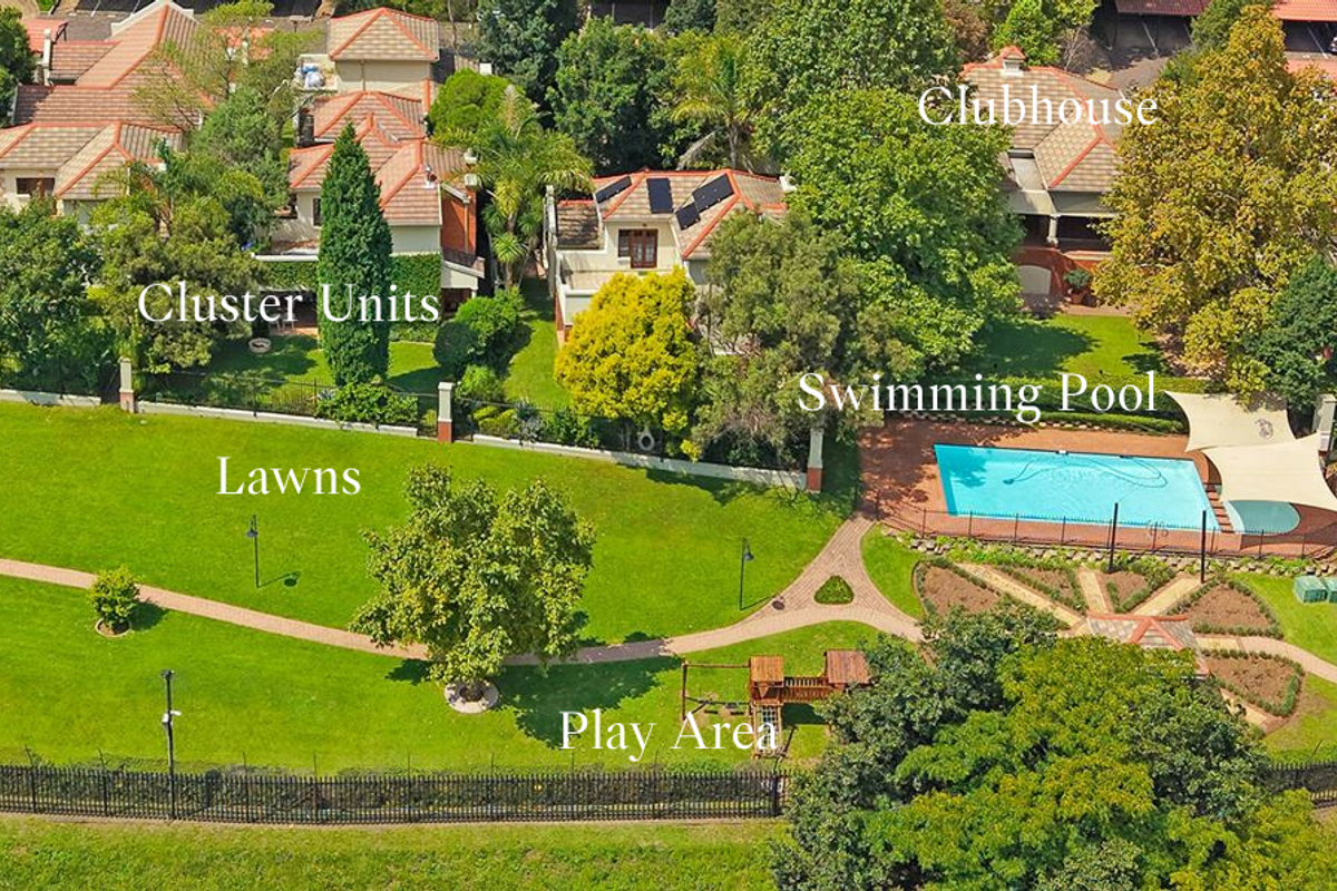 Aerial view of the townhouse complex featuring communal lawns, a swimming pool, clubhouse, and landscaped garden areas.
