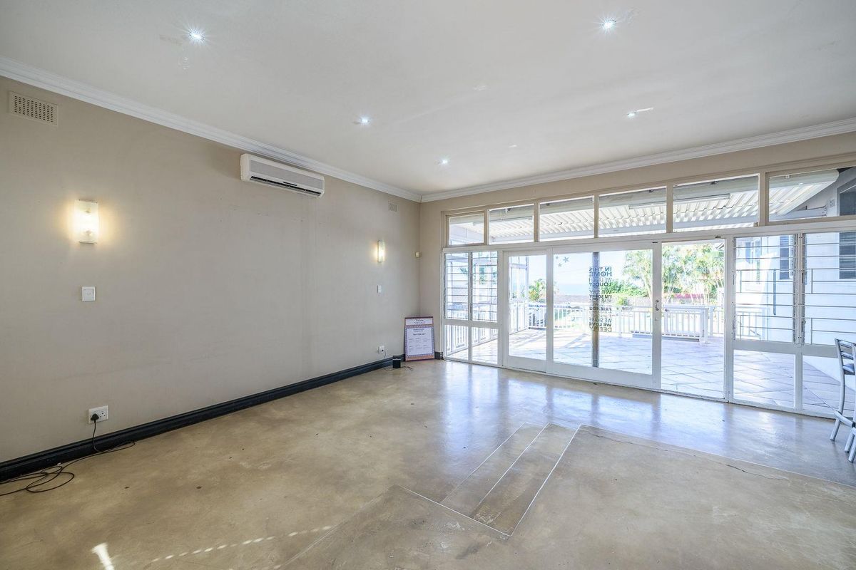 Spacious living area featuring polished concrete floors, recessed lighting, wall sconces, and large sliding glass doors providing access to the outdoor patio.