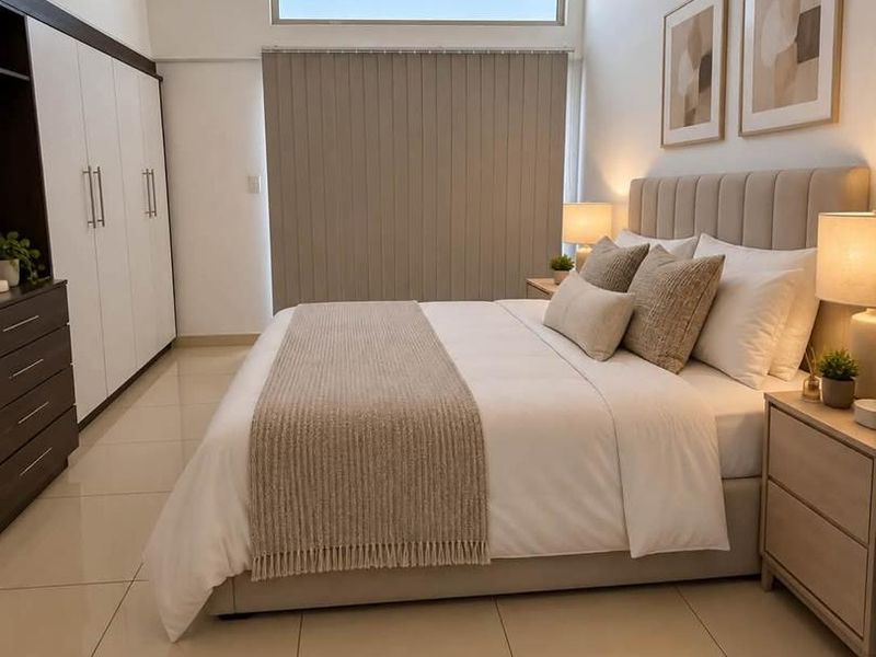 A well-maintained bedroom featuring tiled flooring, built-in cupboards, a high clerestory window for natural light, and an integrated air conditioning unit.