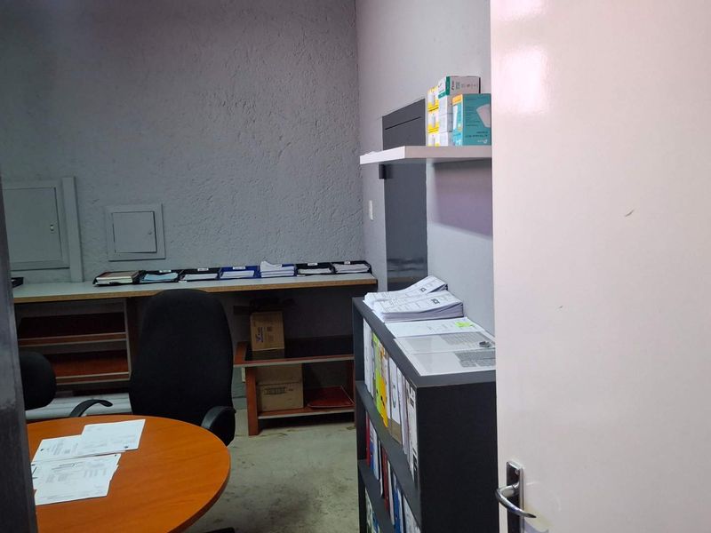 A functional office space featuring a built-in desk, wall-mounted shelving, and textured wall finishes, suitable for administrative or industrial workspace use.