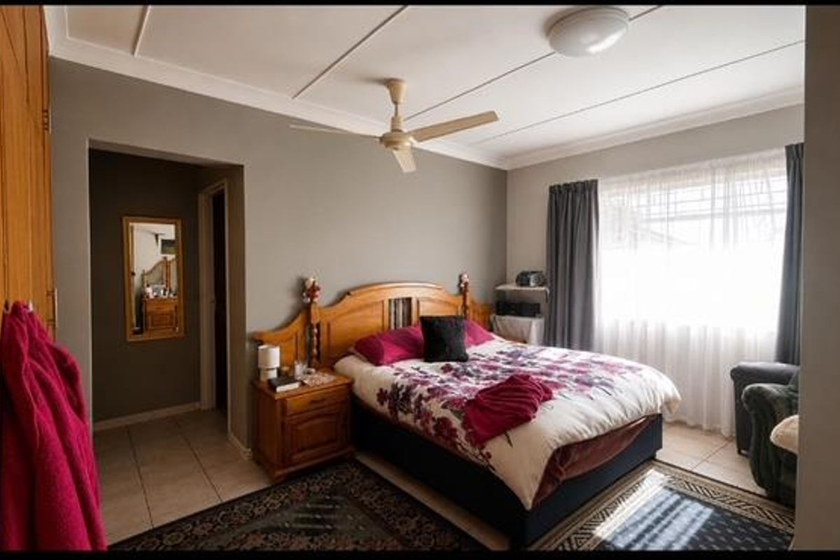 A well-lit bedroom featuring built-in wooden cabinetry, a ceiling fan, and tiled flooring, offering a comfortable and functional living space.