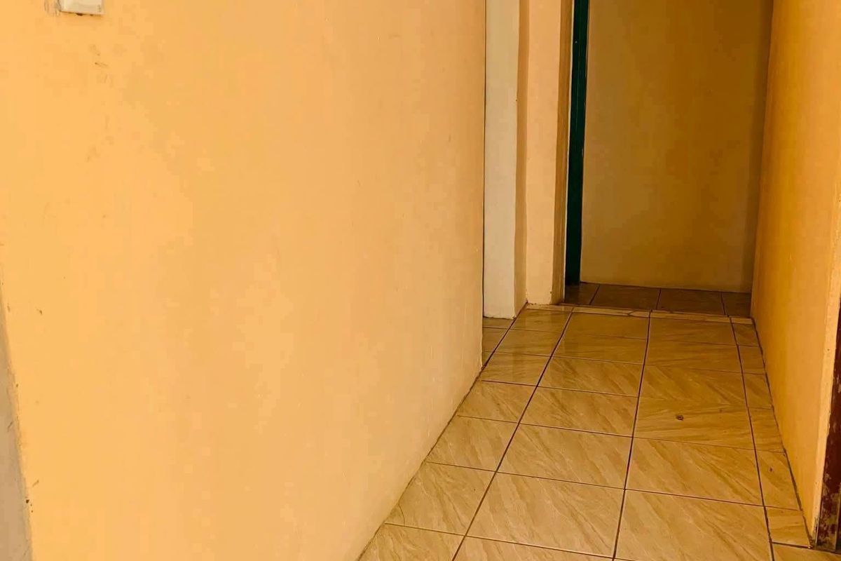 A vacant interior hallway featuring tiled flooring and plain peach-toned walls, providing access to adjacent rooms.