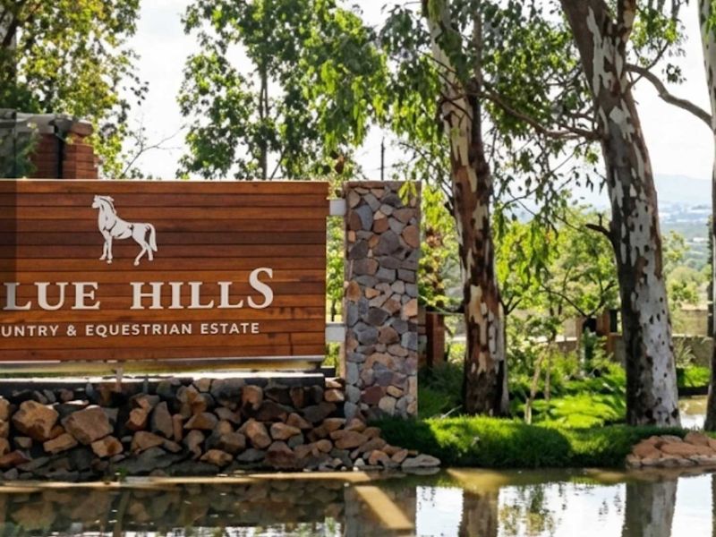 Entrance signage for Blue Hills Country and Equestrian Estate featuring stone masonry and timber detailing set against a landscaped water feature.