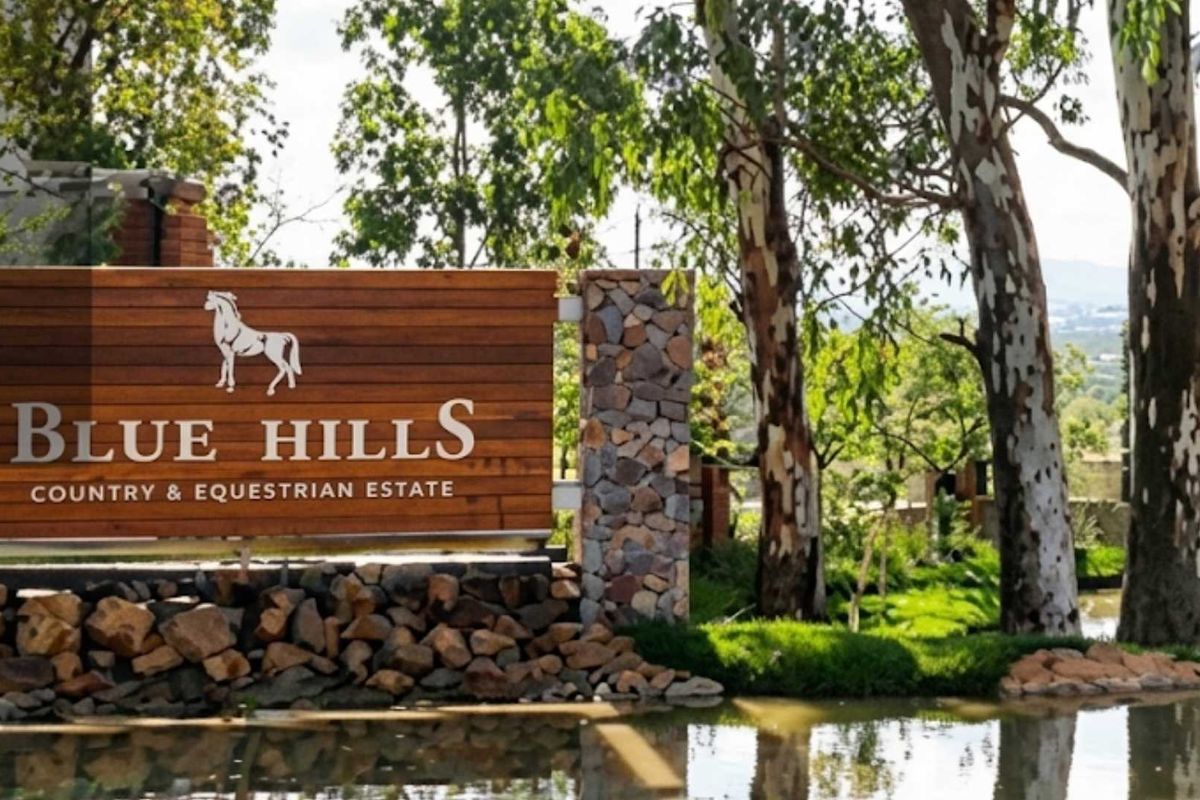 Entrance signage for Blue Hills Country and Equestrian Estate featuring stone masonry and timber detailing set against a landscaped water feature.