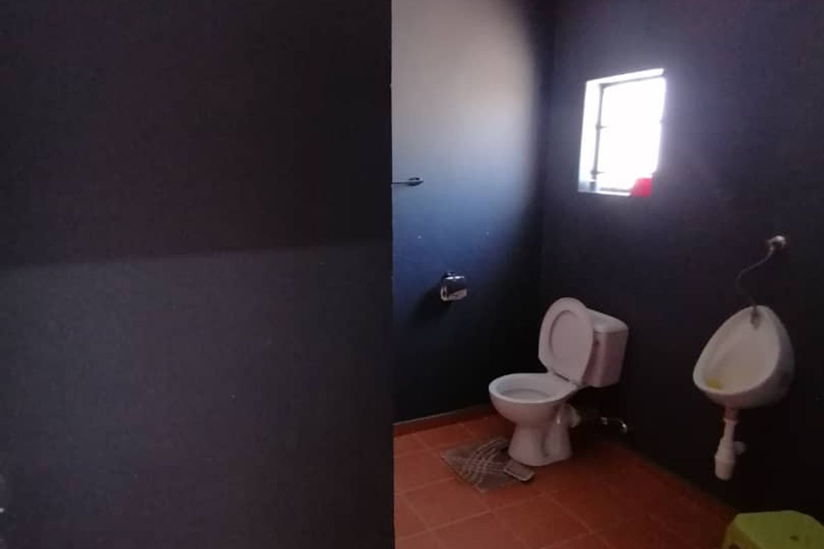 A functional commercial restroom facility featuring a standard toilet, wall-mounted urinal, and tiled flooring.