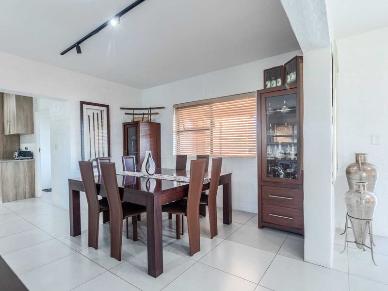 Open-plan dining area featuring neutral tiled flooring, track lighting, and seamless flow into the adjacent kitchen space.