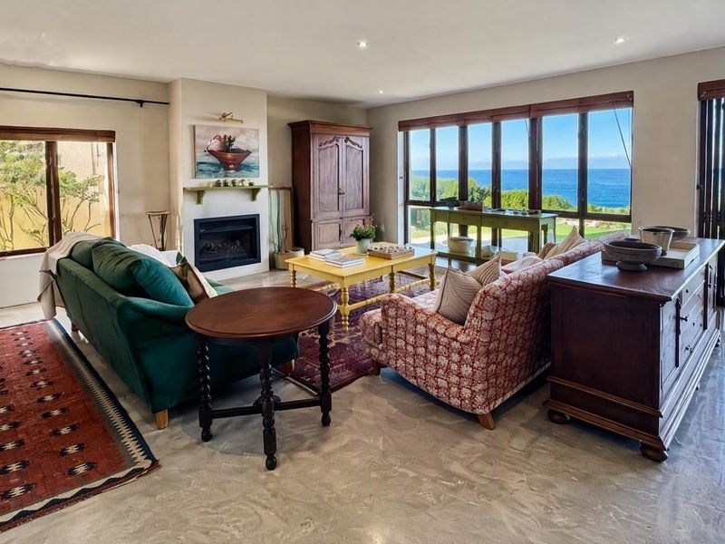 Spacious living room featuring polished concrete floors, a built-in fireplace, and expansive glass doors offering panoramic ocean views.