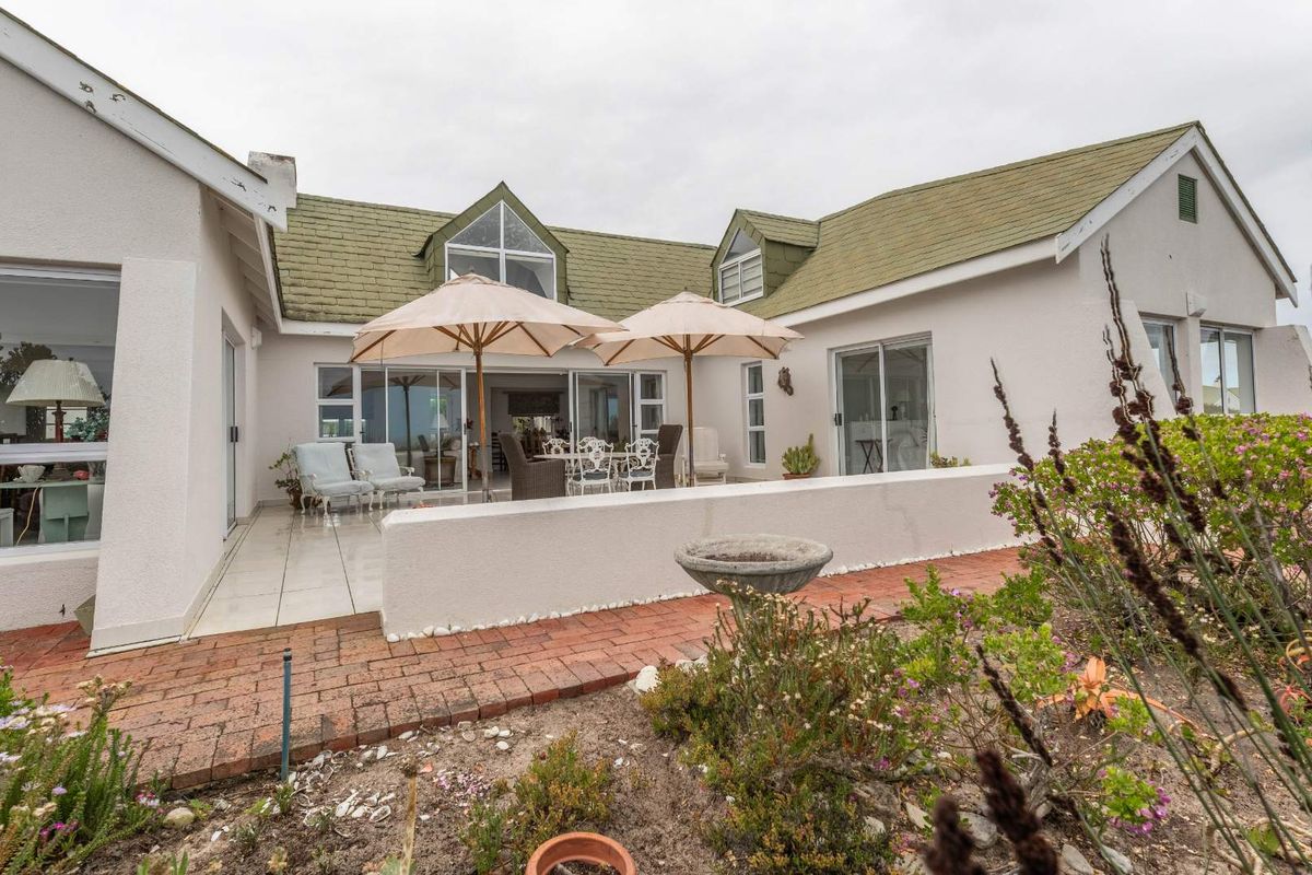 Rear view of the house featuring a paved patio area, sliding glass doors, and a landscaped garden with brick pathways.