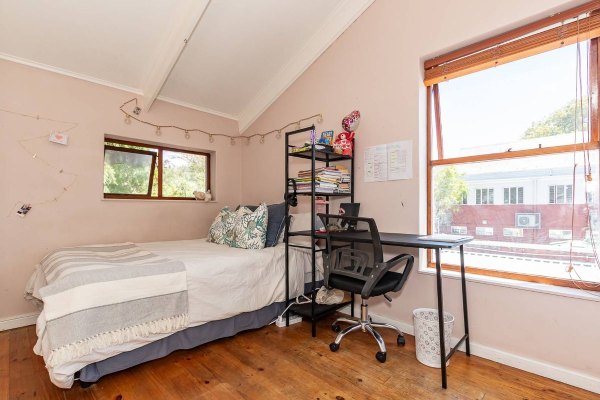 A bedroom featuring vaulted ceilings, timber flooring, and dual aspect windows providing natural light.