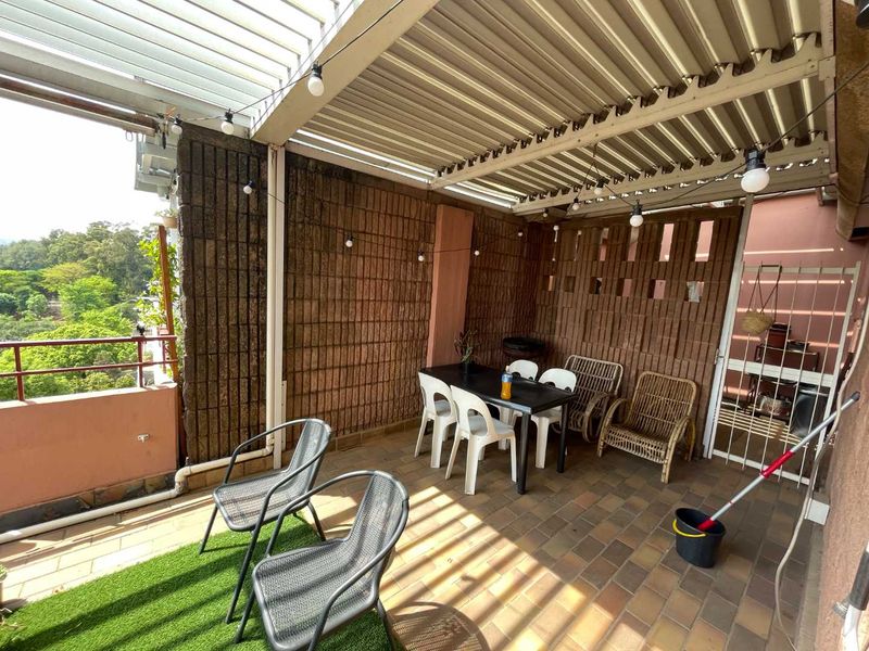Covered balcony featuring a louvre roof, brick feature wall, and tiled flooring, offering an outdoor space with views.