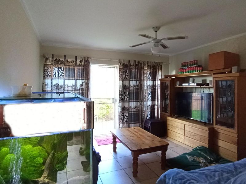 A living room featuring tiled flooring, a ceiling fan, and a sliding glass door providing access to an outdoor area.