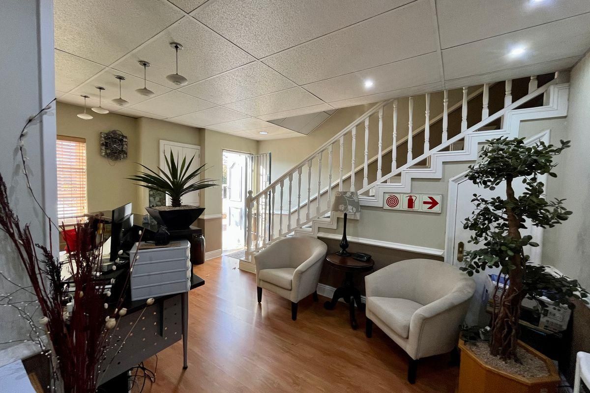 A welcoming entrance area featuring a staircase with a white balustrade, drop ceiling, and laminate flooring, providing access to the main building levels.