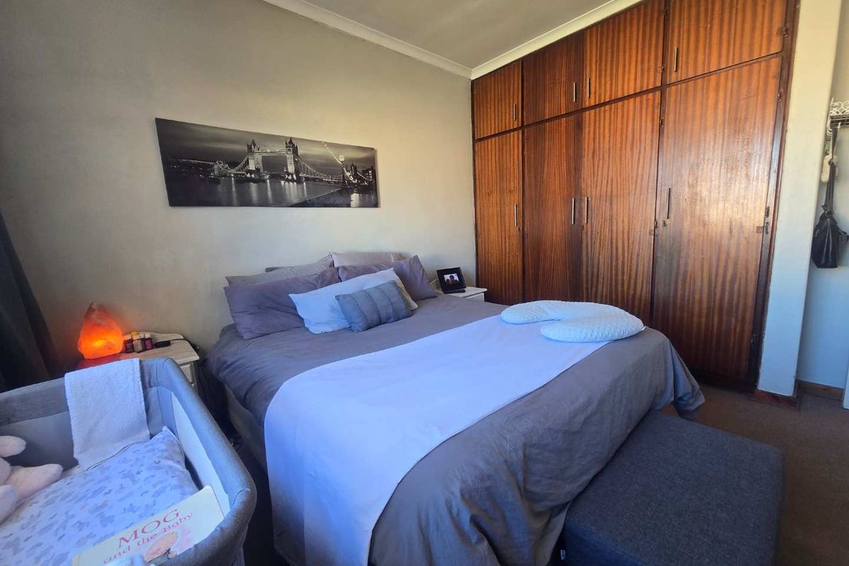 A bedroom featuring floor-to-ceiling built-in wooden wardrobes, providing ample storage space within a functional and neutrally painted room.