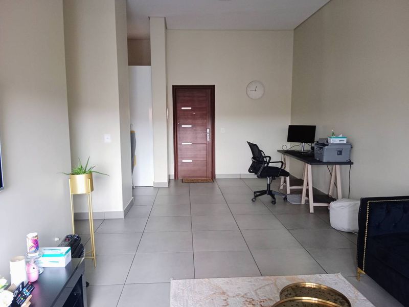 A spacious living area featuring neutral wall tones and large format floor tiles, providing a clean and versatile foundation for interior design.