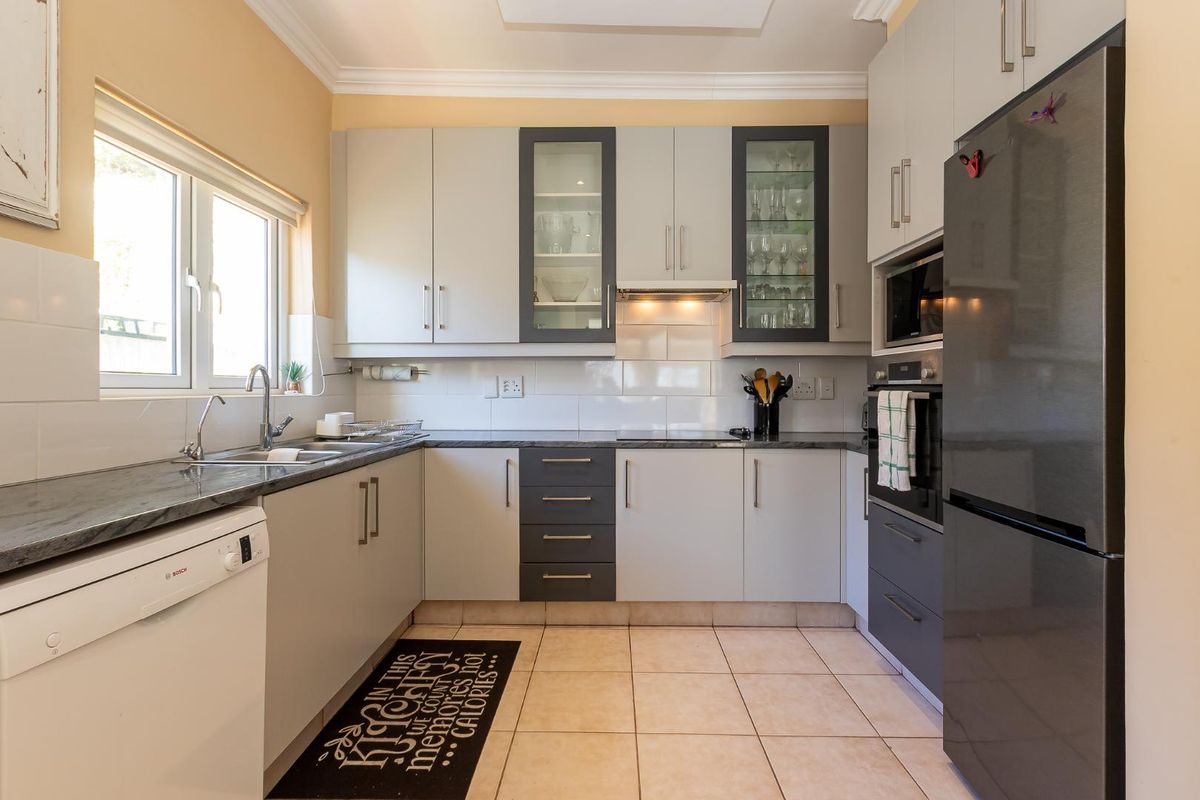 A well-maintained kitchen featuring modern cabinetry, stone-look countertops, tiled splashbacks, and integrated appliances including an oven and extractor fan.