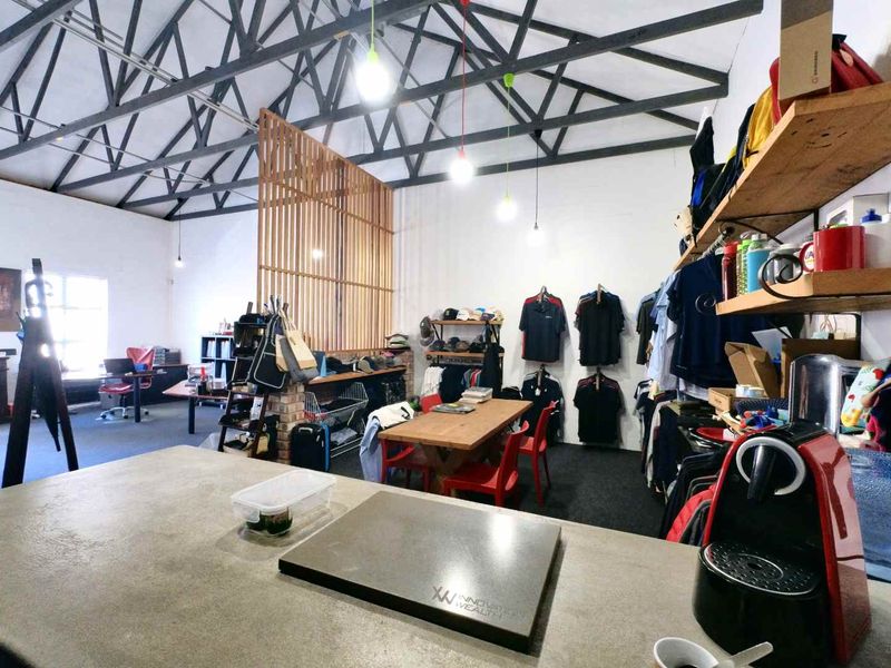 Spacious open-plan industrial office area featuring exposed steel roof trusses, a concrete countertop, and a timber slat room divider.
