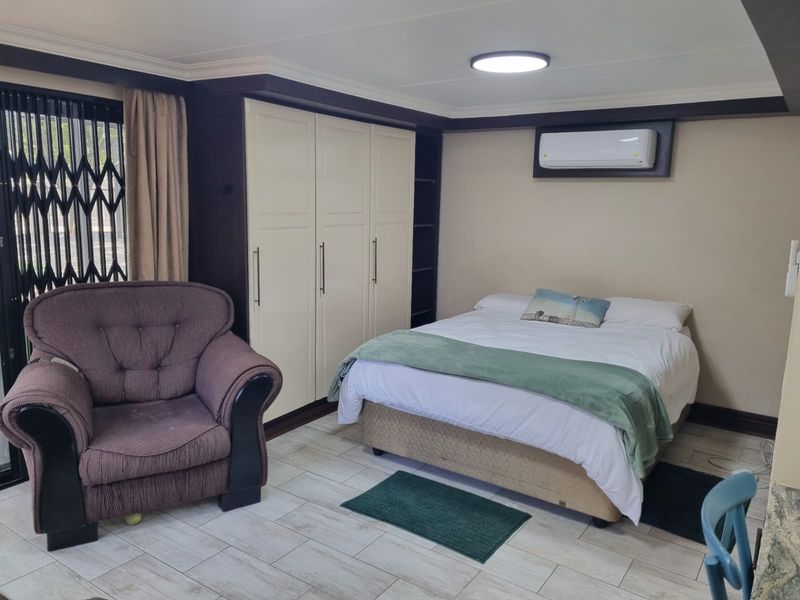A well-maintained bedroom featuring built-in cupboards, tiled flooring, and a wall-mounted air conditioning unit, providing a comfortable and functional living space.