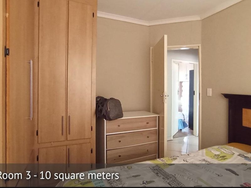 A bedroom featuring a built-in wardrobe and neutral wall finishes, providing a functional space with direct access to the hallway.