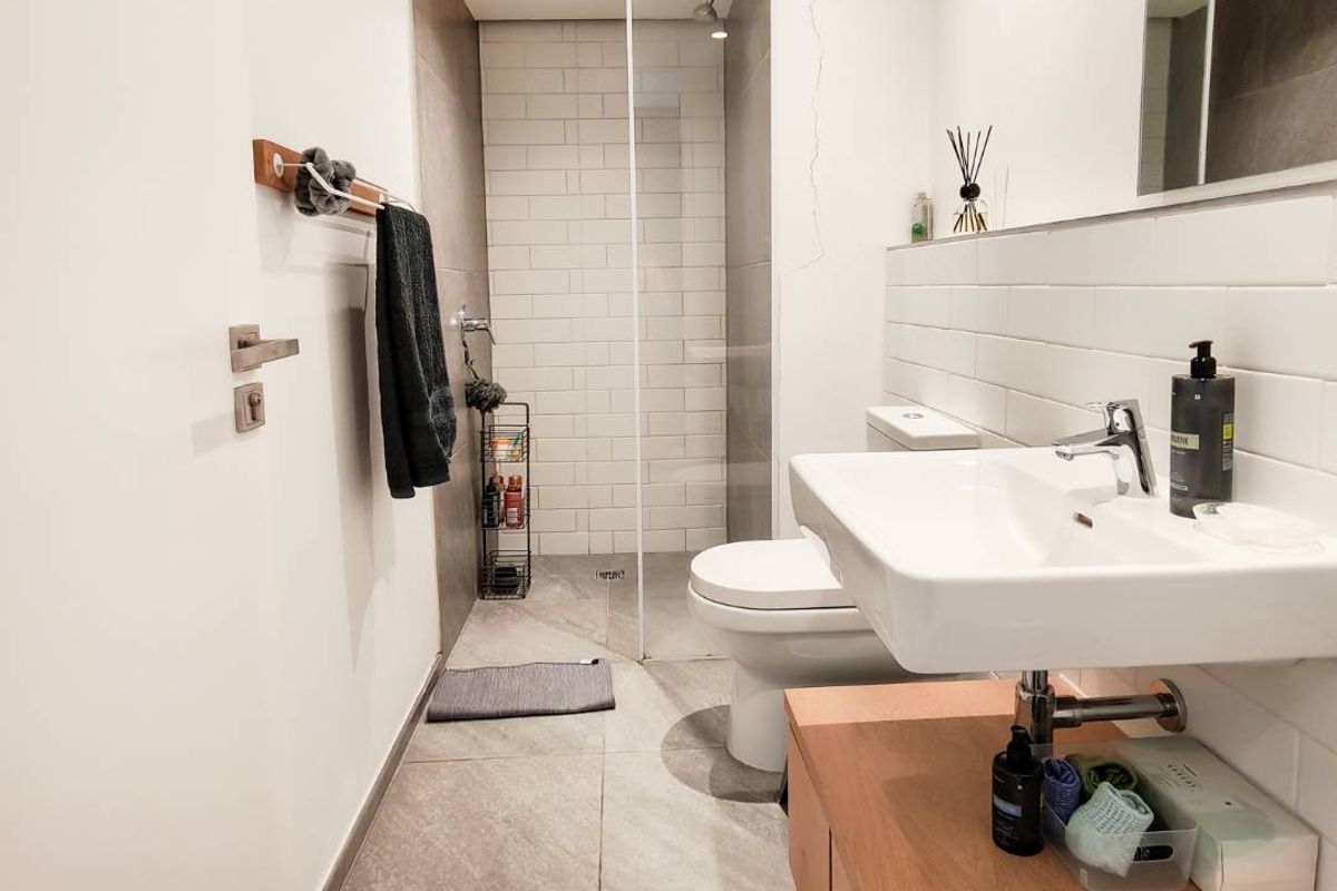 Modern bathroom featuring a walk-in shower with glass screen, wall-mounted basin with vanity cabinet, and neutral tiled finishes.
