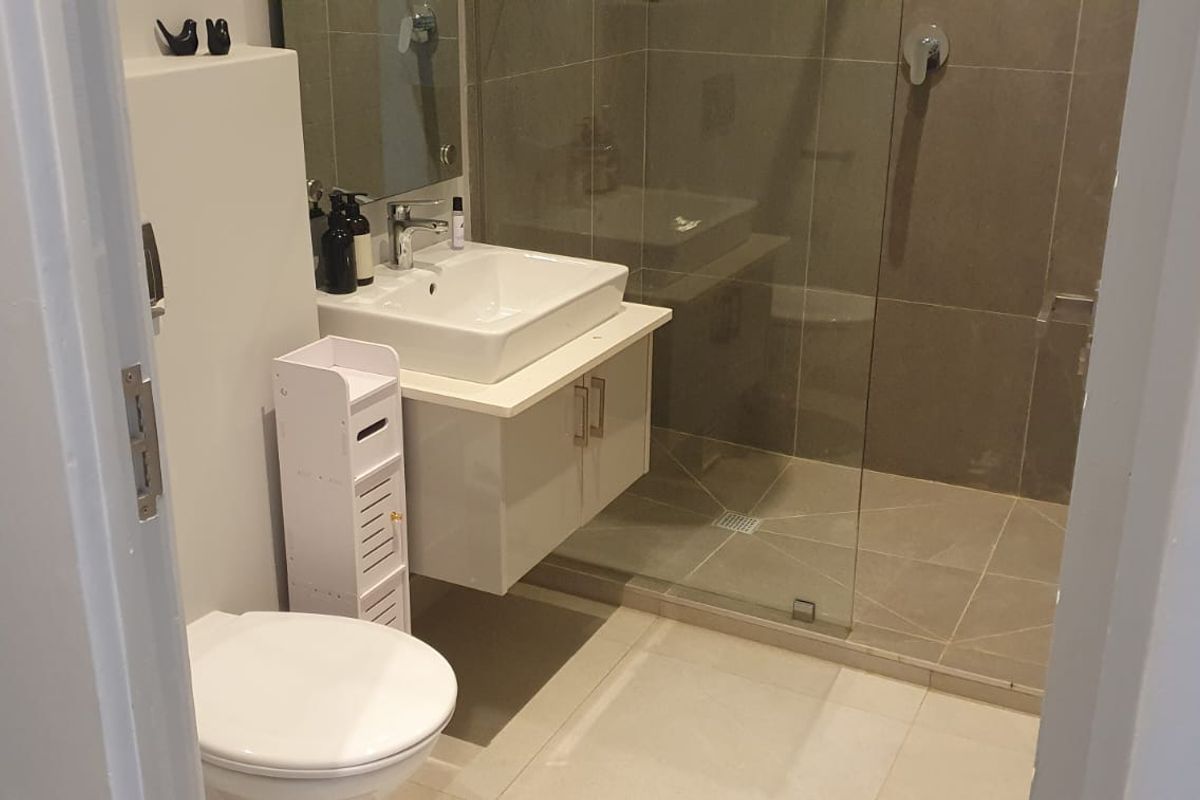 Modern bathroom featuring a wall-mounted vanity with a ceramic basin, a glass-enclosed shower with tiled walls, and contemporary fixtures.