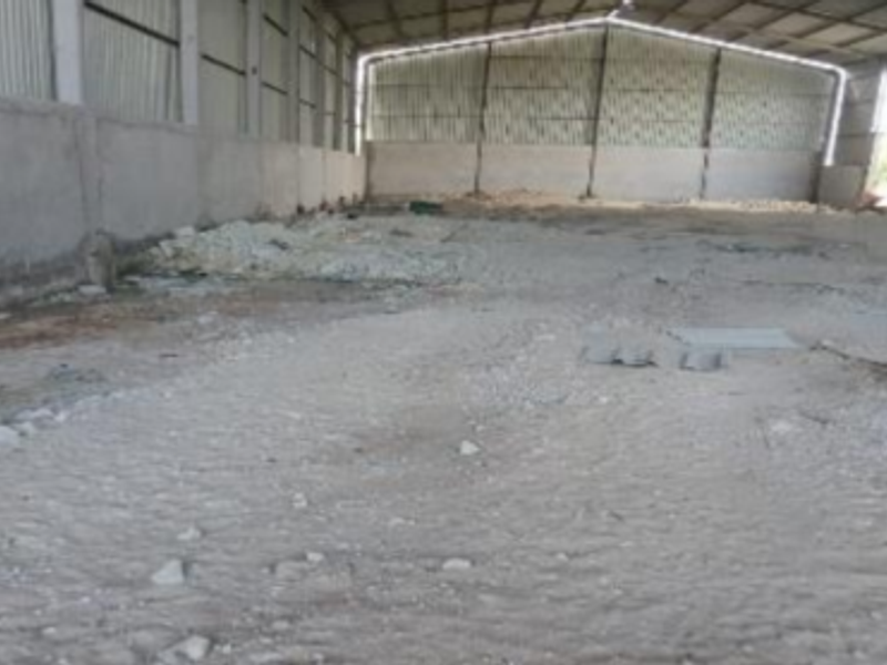 Large industrial warehouse space featuring a steel frame structure, corrugated metal roofing, and concrete perimeter walls, currently in a shell condition.