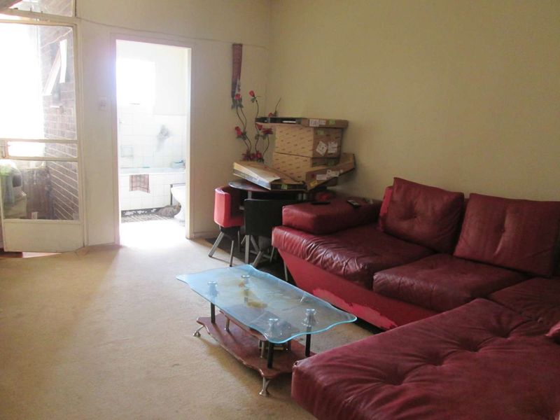 A living room area featuring carpet flooring and access to an adjacent bathroom, requiring cosmetic updates to improve the overall condition.