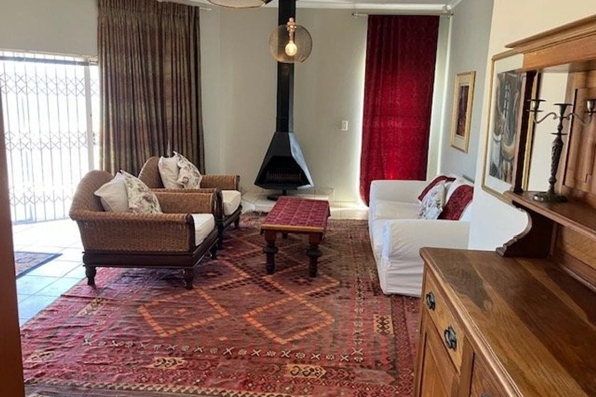 A comfortable living room featuring a central freestanding fireplace, tiled flooring, and direct access to an outdoor area through a security-fitted sliding door.
