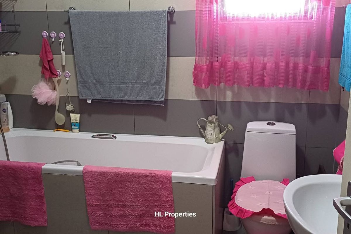 A functional bathroom featuring a bathtub with shower mixer, a standard toilet, and a pedestal basin with tiled wall finishes.