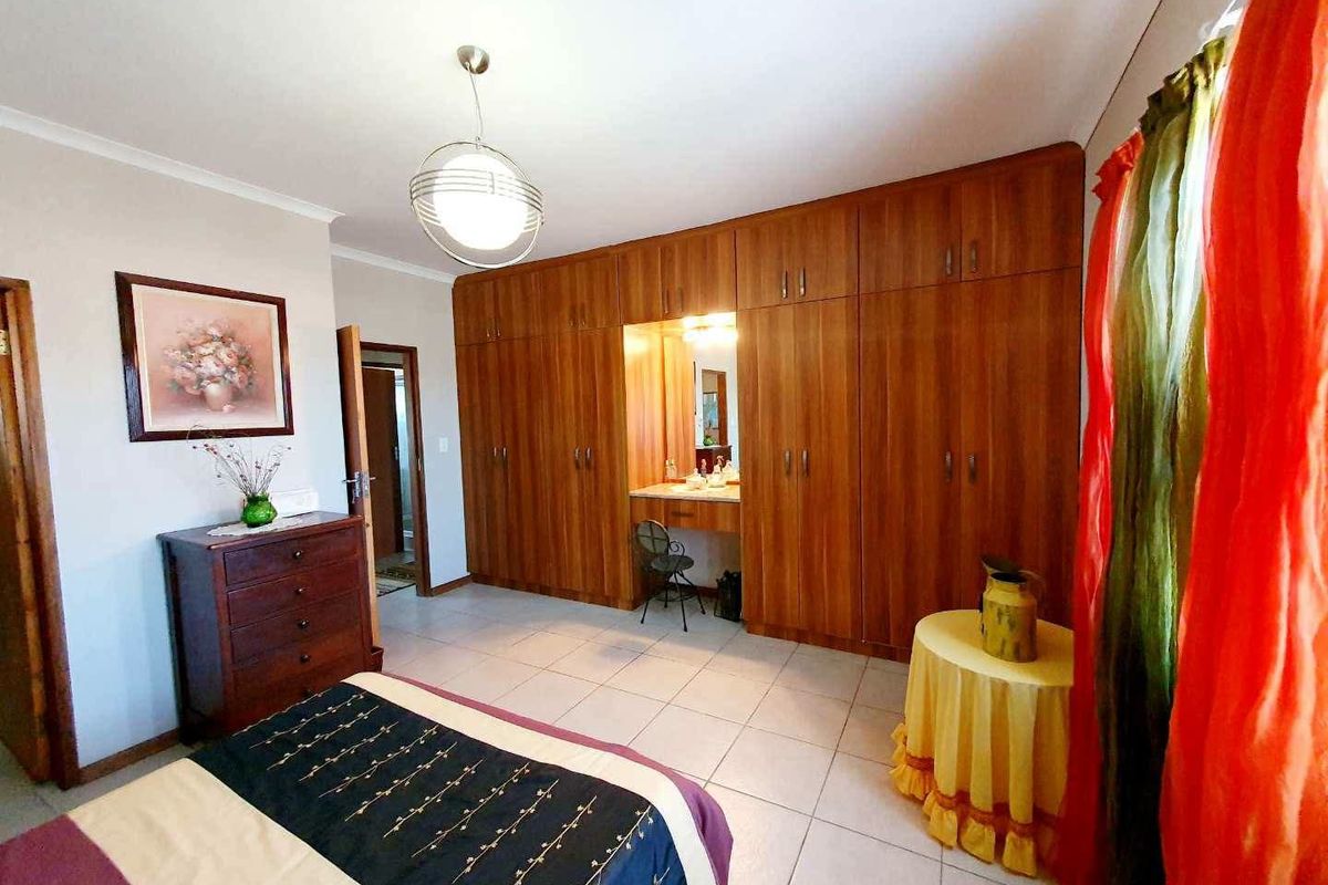 Spacious bedroom featuring extensive built-in wooden cabinetry with an integrated vanity station and neutral tiled flooring.