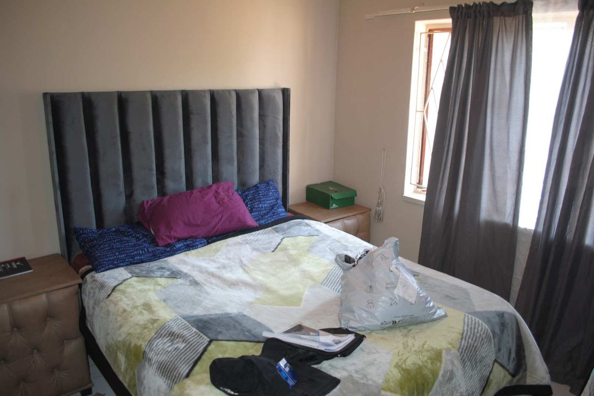 A bedroom featuring a window with security bars and neutral wall finishes.