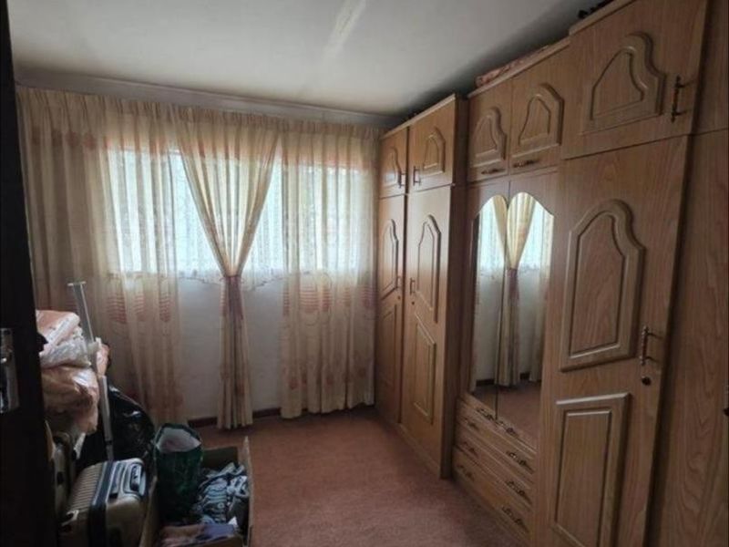 A bedroom featuring built-in wooden cupboards and carpeted flooring, offering potential for modernization and updated finishes.