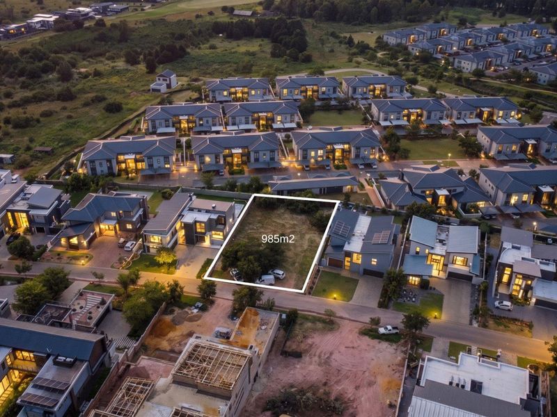 An aerial view of a 985m2 vacant residential plot situated within a developed estate, ready for new construction.