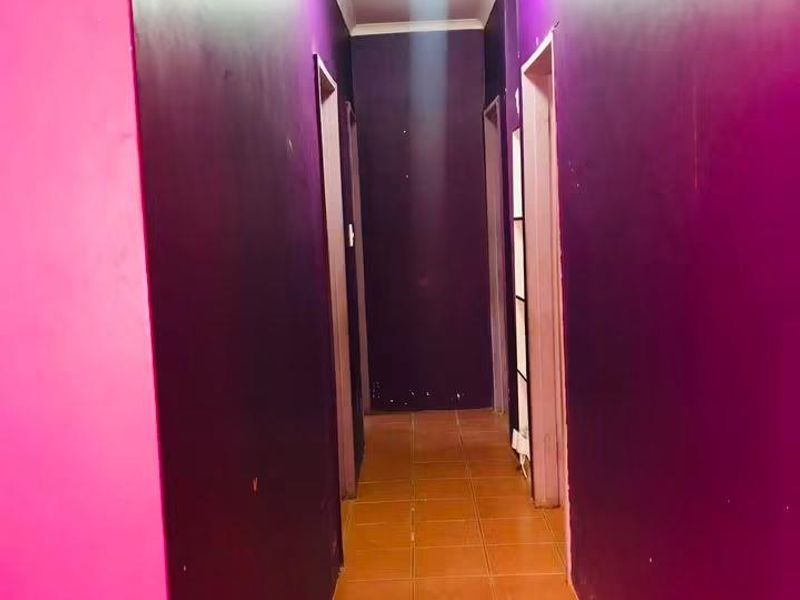 A narrow residential hallway featuring tiled flooring and multiple doorways, currently finished with bold, high-contrast wall paint.