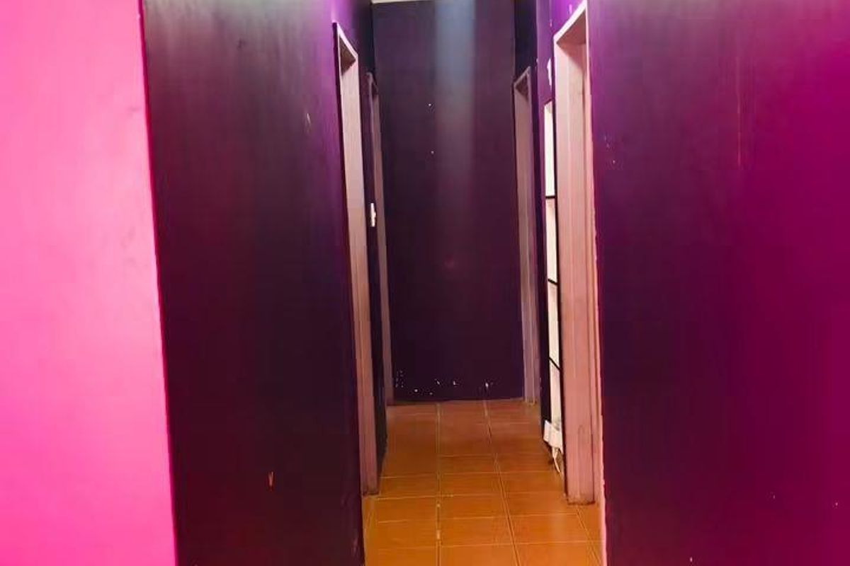 A narrow residential hallway featuring tiled flooring and multiple doorways, currently finished with bold, high-contrast wall paint.