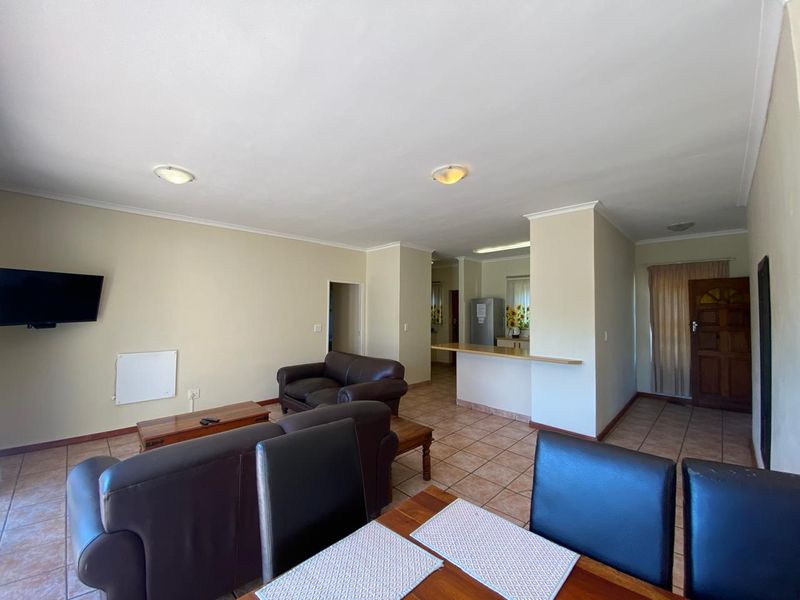 Open-plan living and dining area featuring tiled flooring, a breakfast bar, and direct access to the front entrance.